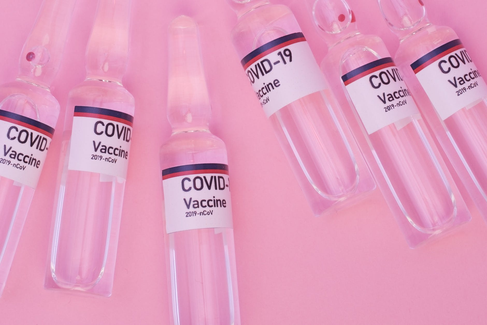 coronavirus vaccine in glass ampoules on pink surface