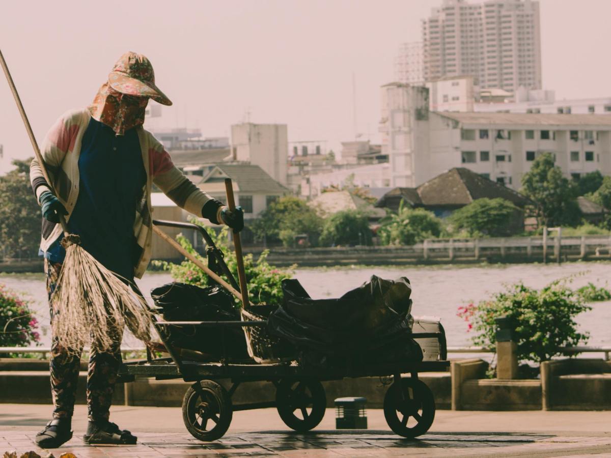 person holding broom and cart