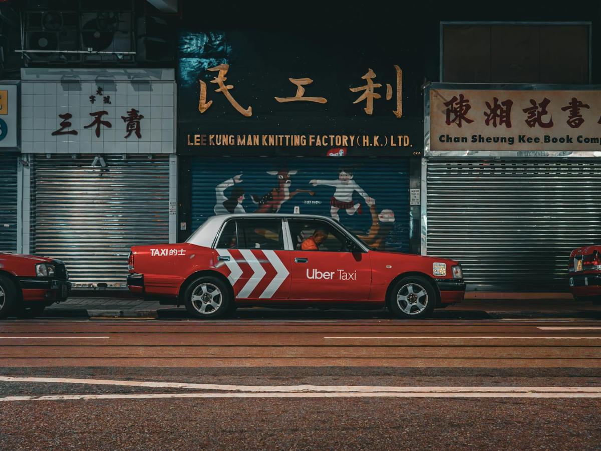 red taxi parked on the side of a road in hong kong