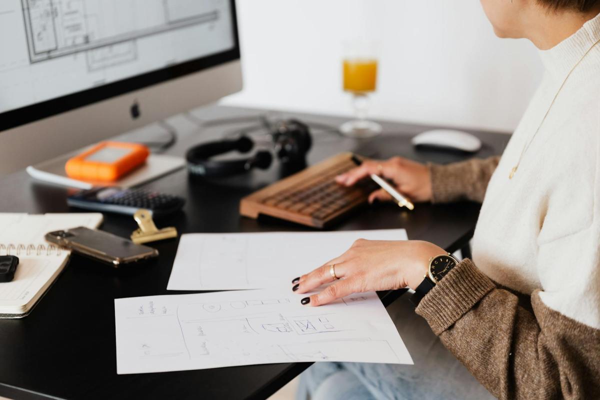crop anonymous woman working with documents sitting at table with computer