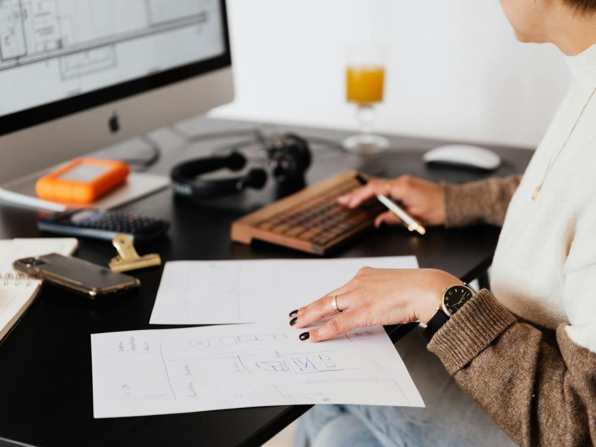 crop anonymous woman working with documents sitting at table with computer