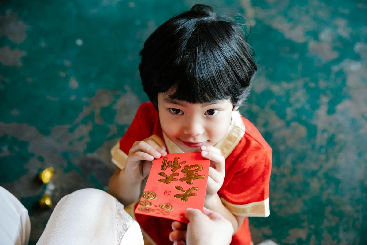 an adult giving a red envelope to a young boy