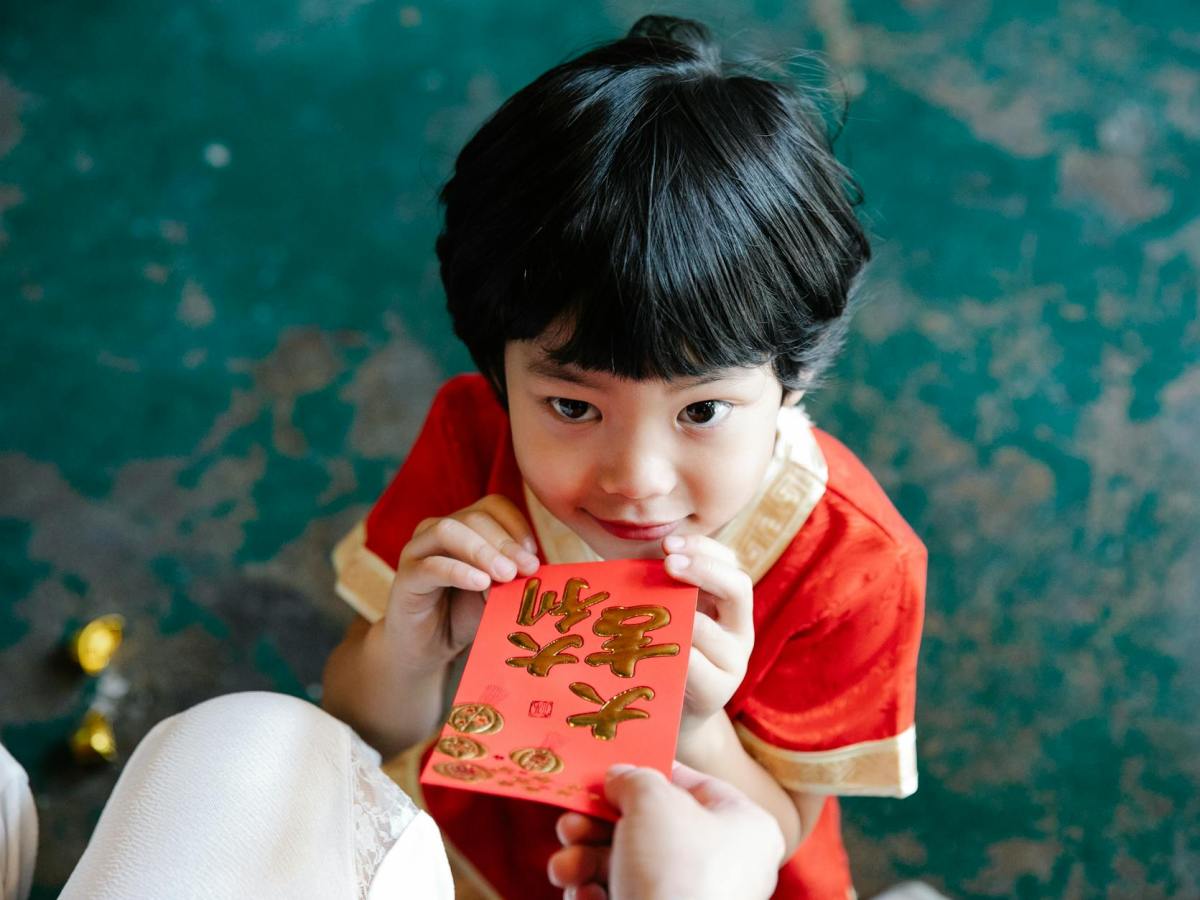 an adult giving a red envelope to a young boy