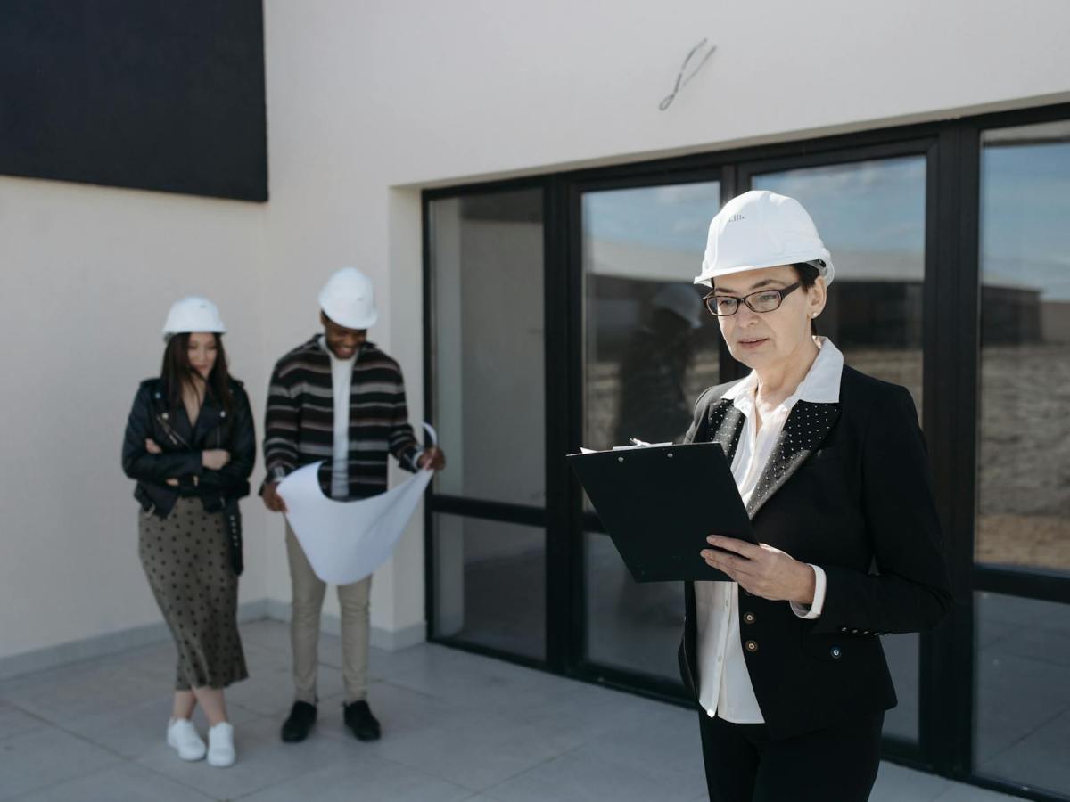seller in suit and clients standing by house windows