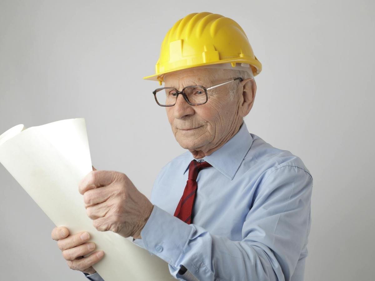senior male engineer reading blueprint in studio