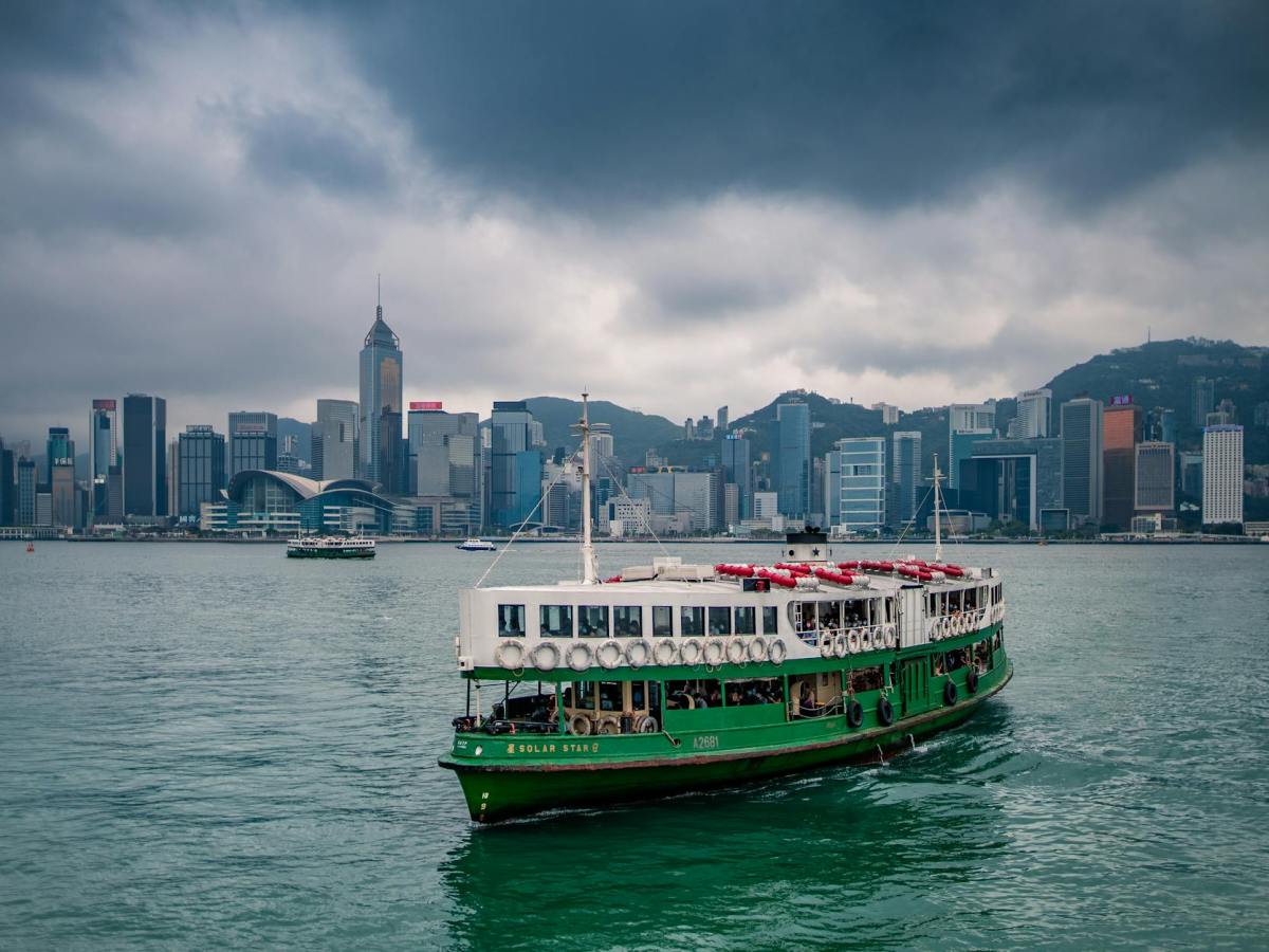 green and white ferry boat sailing near city buildings