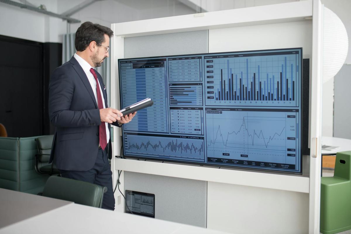 man in corporate attire looking at a wide screen monitor