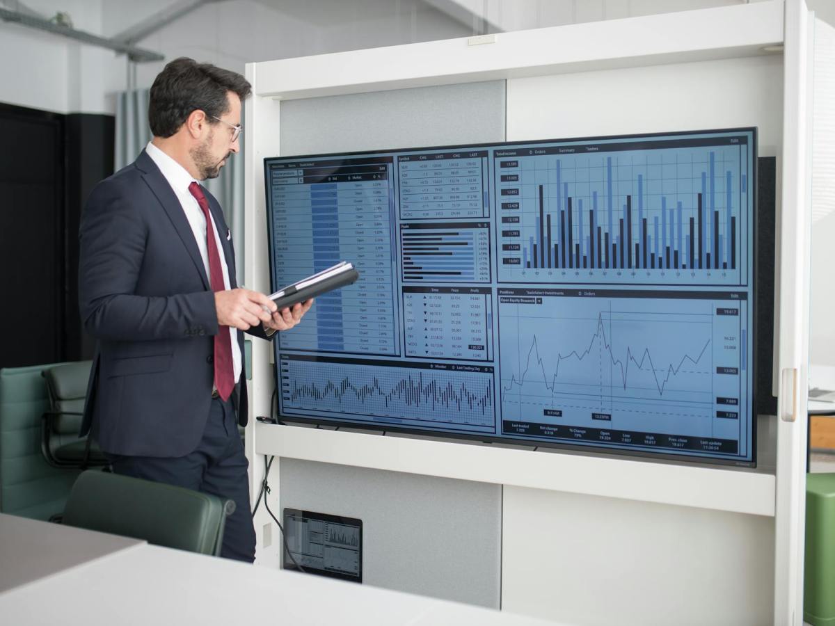 man in corporate attire looking at a wide screen monitor
