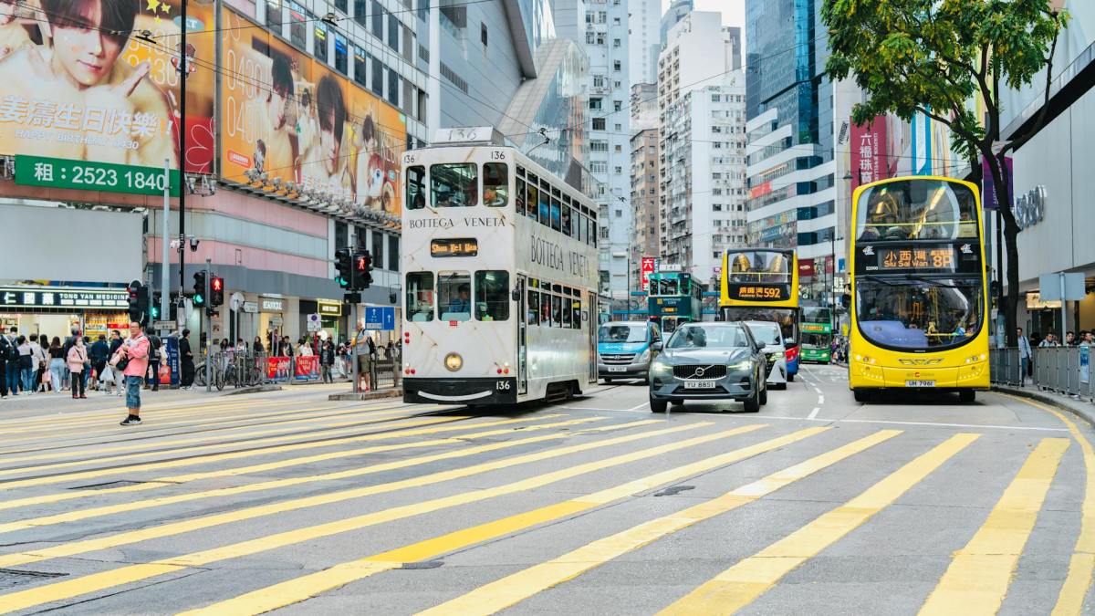 busy street scene in hong kong with tram and buses