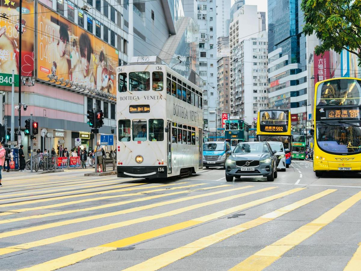 busy street scene in hong kong with tram and buses
