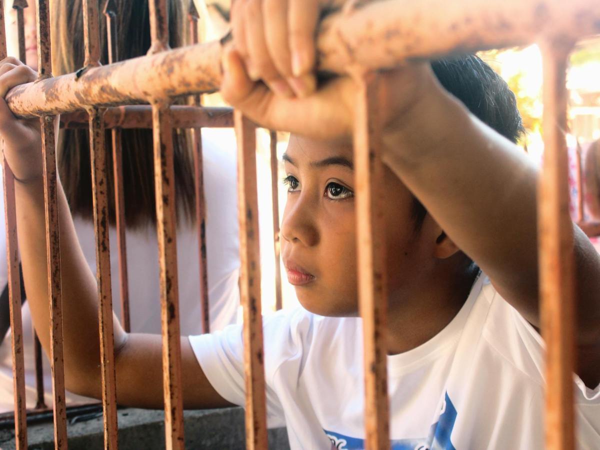 child in cage holding bars