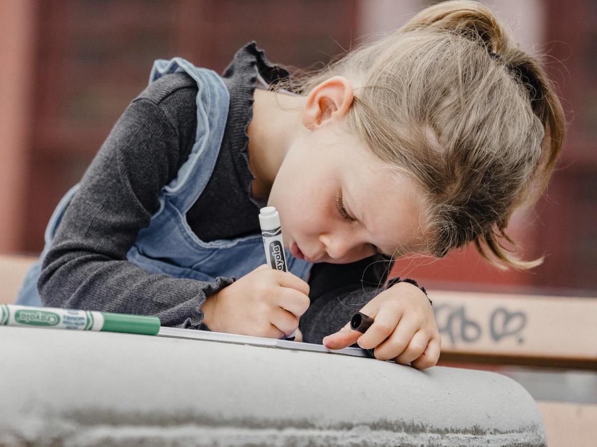 focused little girl drawing with markers