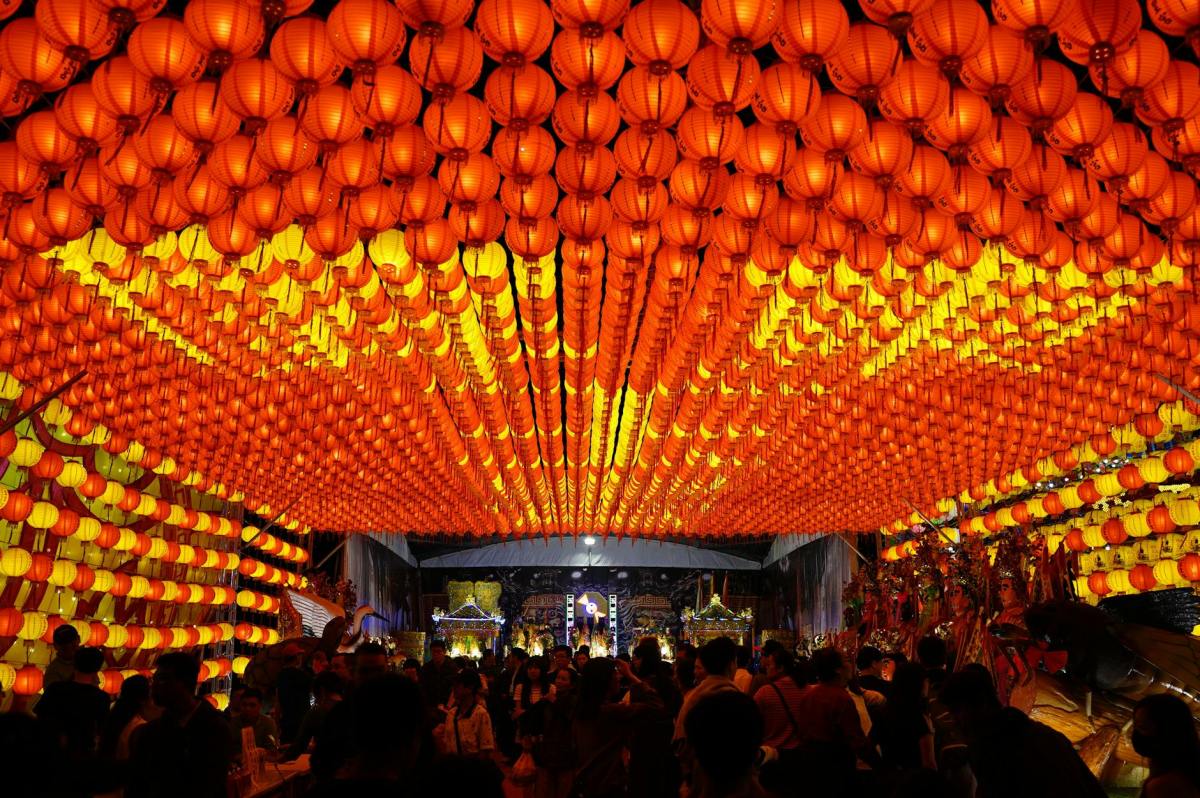 people standing near orange paper lanterns during night time