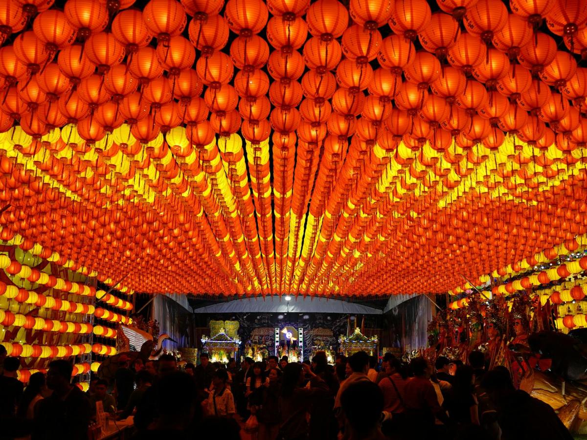 people standing near orange paper lanterns during night time