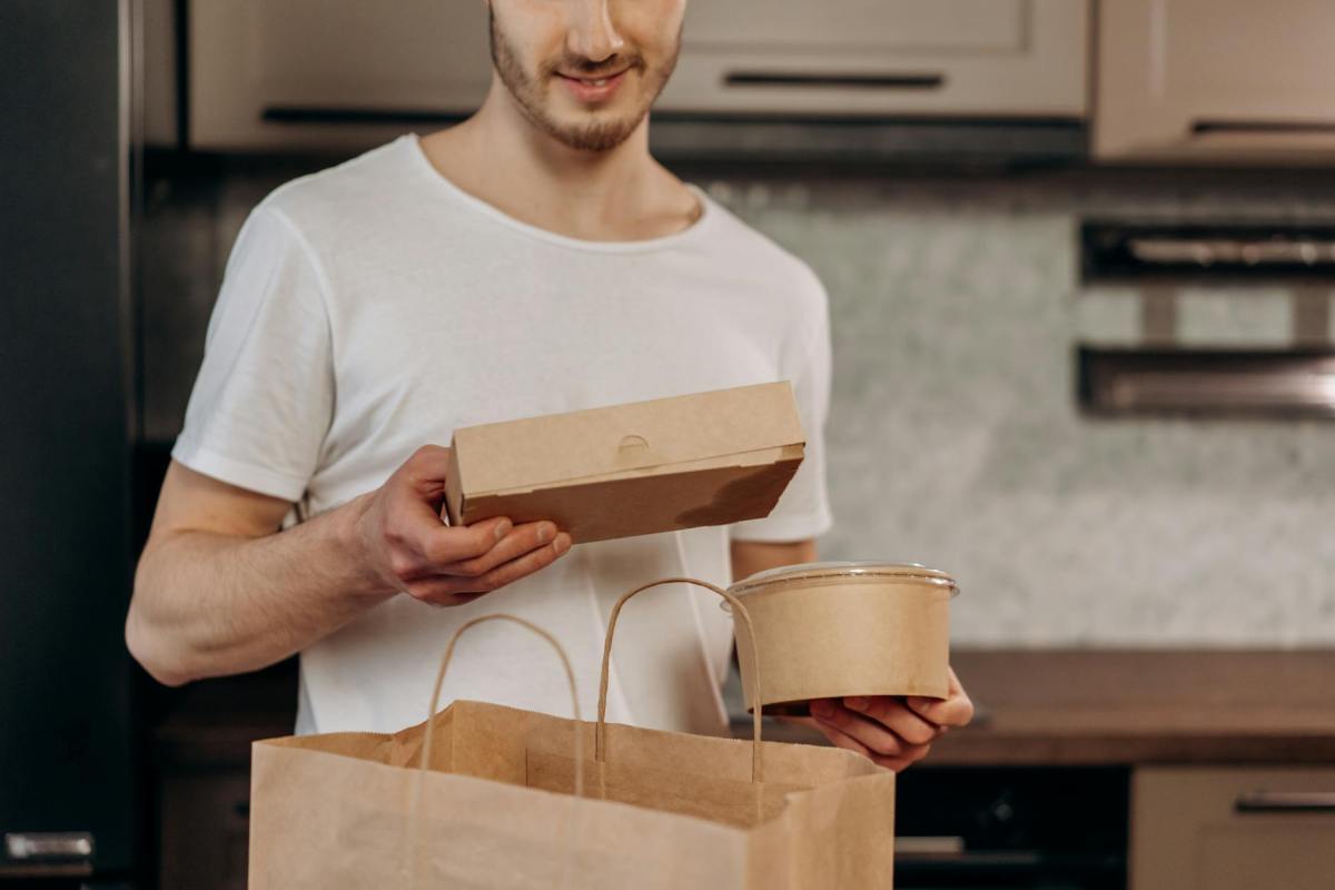 a man in white shirt taking out food delivery from the bag
