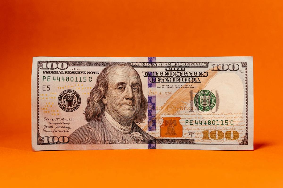 close up of a one hundred dollar bill with an orange background