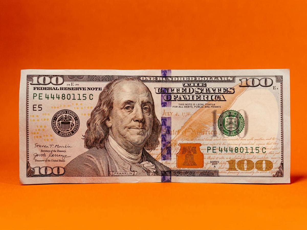 close up of a one hundred dollar bill with an orange background