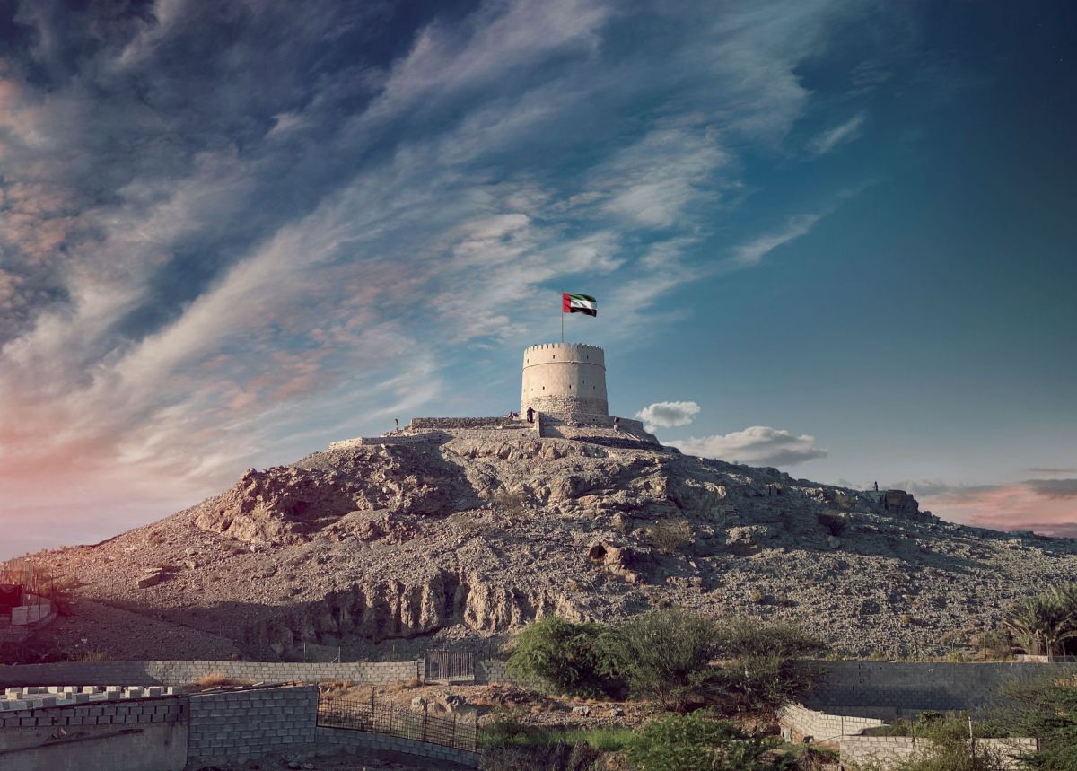tower with flag under cloudscape sharjah united arab emirates