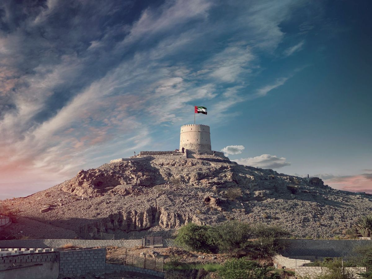 tower with flag under cloudscape sharjah united arab emirates