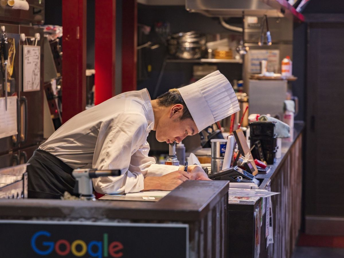 chef writing notes in a busy restaurant kitchen