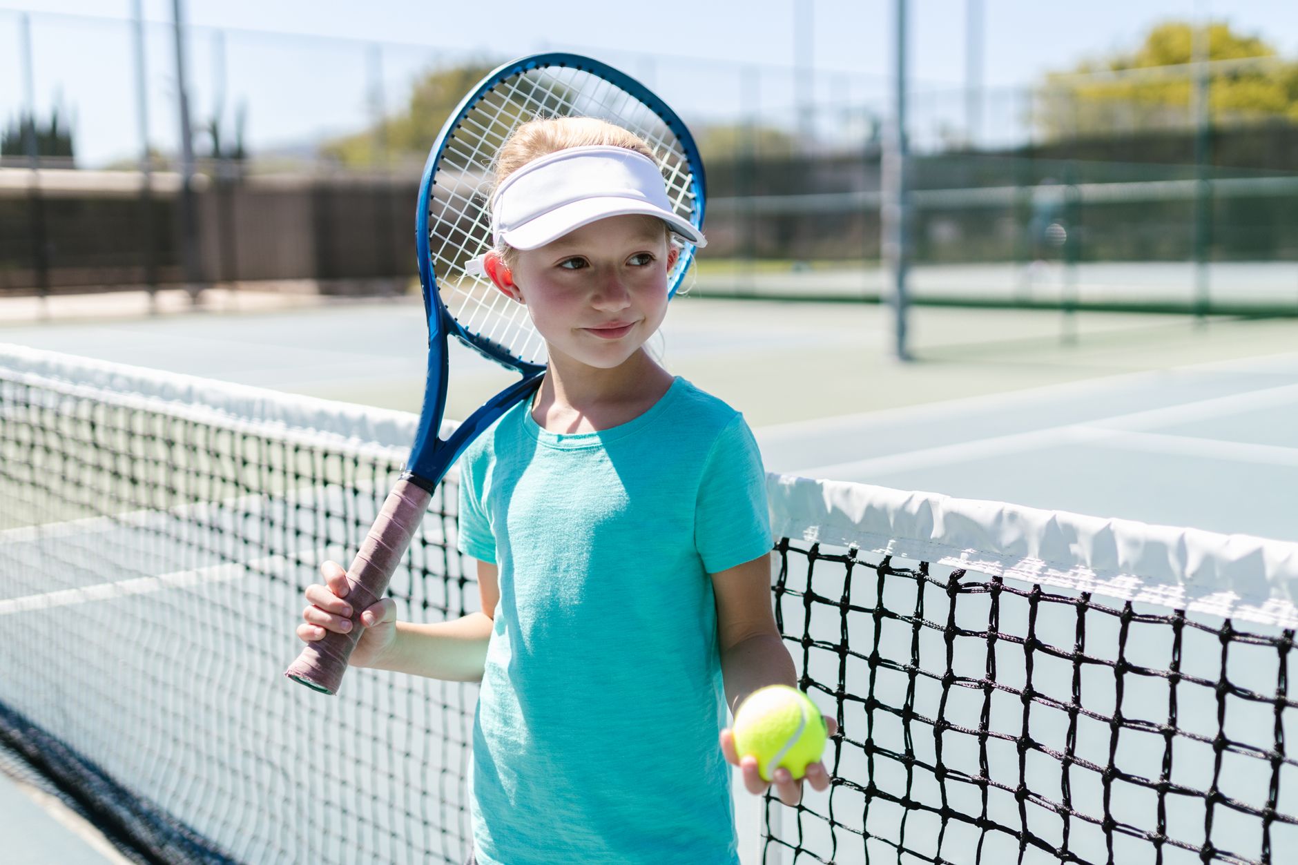 girl wearing sportswear standing by the tennis net